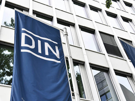 Flagge mit der Aufschrift DIN vor der Fassade eines Gebäudes
