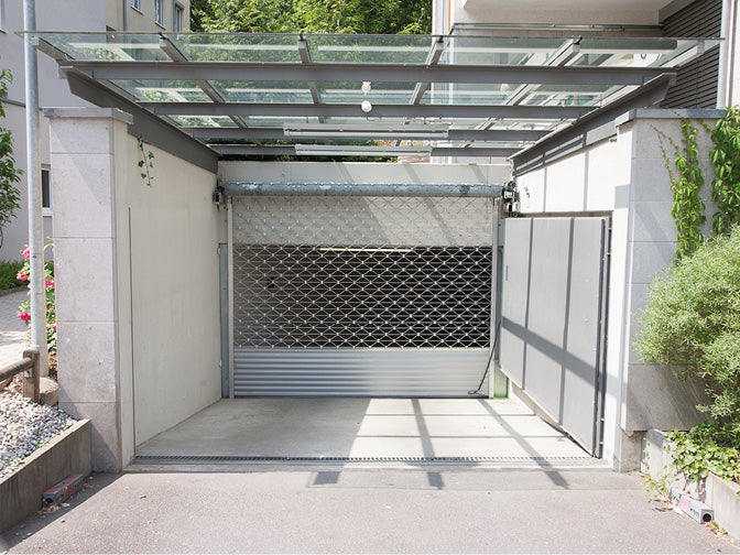 Tiefgaragenzufahrt mit Metallgitter und Glasdach