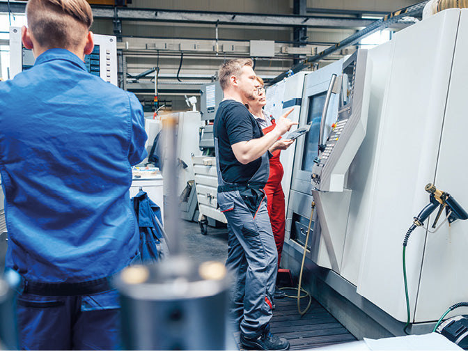 Mehrere Personen an einer CNC Maschine