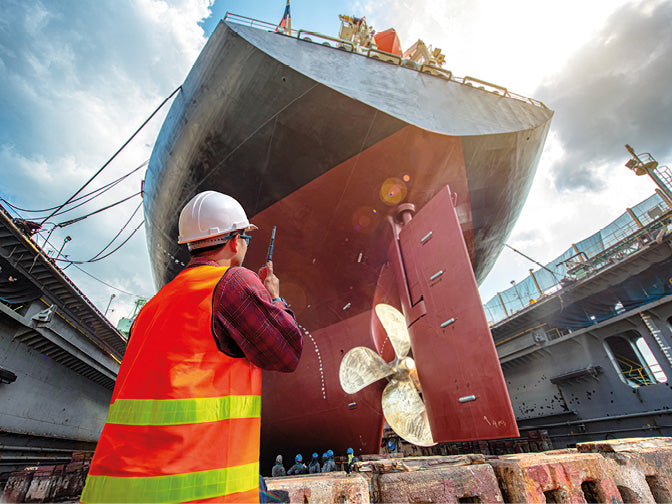 Arbeiter in einem Trockendock in einer Werft mit großem Schiff