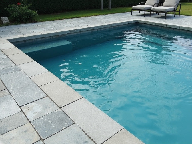 Poolumrandung aus Steinfliesen mit Gartenmöbeln