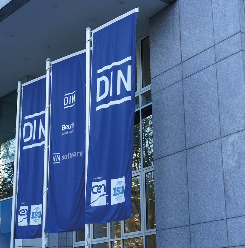 Flaggen in blau mit der Aufschrift "DIN) vor einem Gebäude