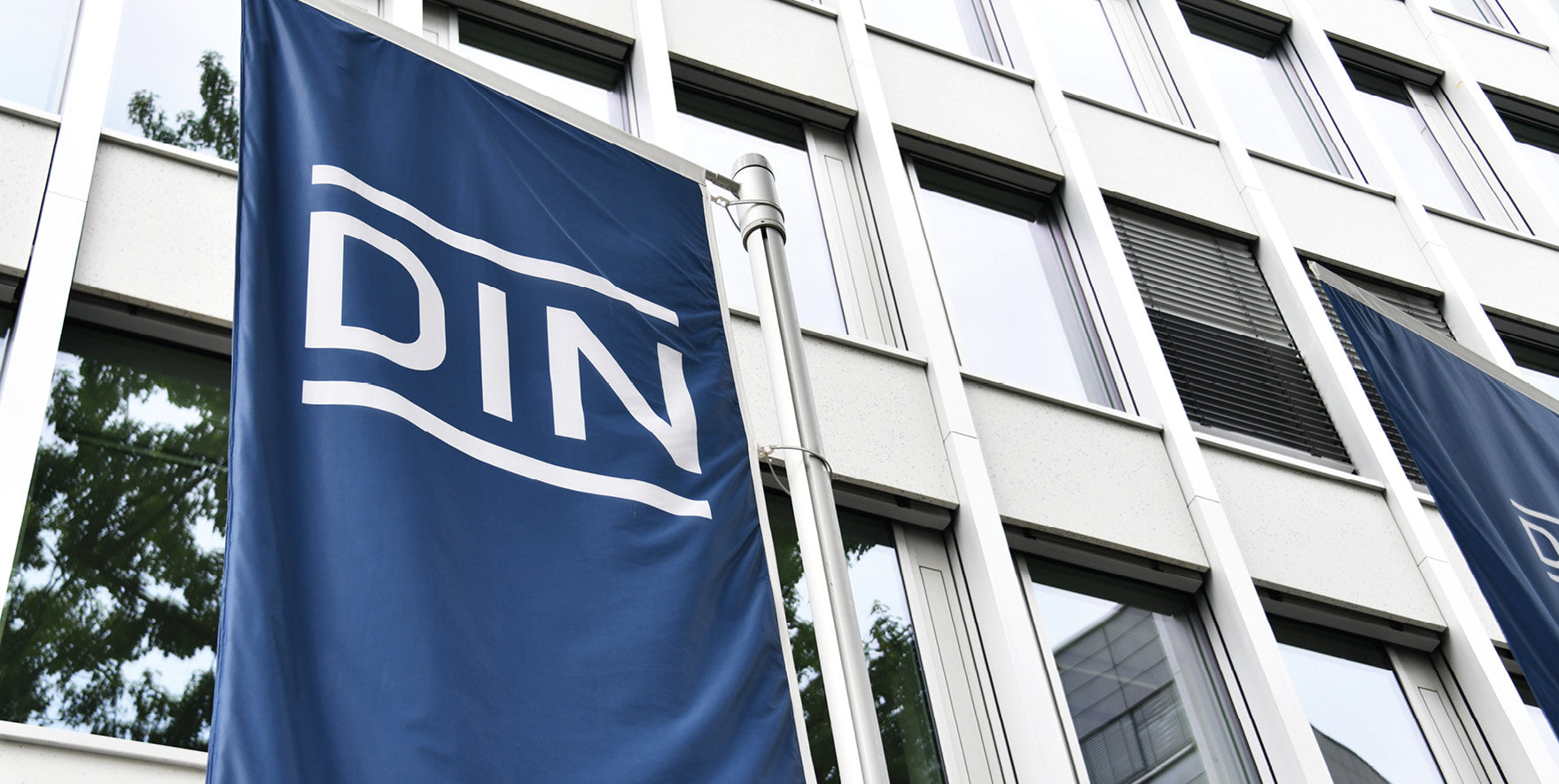 Flagge mit der Aufschrift DIN vor Gebäudefassade