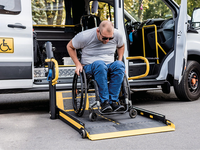 Ein Mann in einem Rollstuhl auf einer Rampe an einem Fahrzeug